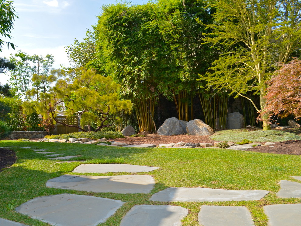 Diseño de jardín asiático grande en patio trasero con exposición parcial al sol y adoquines de piedra natural