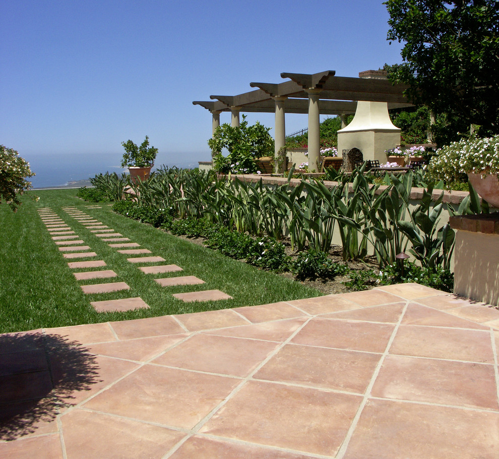 Идея дизайна: большой солнечный участок и сад на заднем дворе в средиземноморском стиле с садовой дорожкой или калиткой, хорошей освещенностью и покрытием из каменной брусчатки