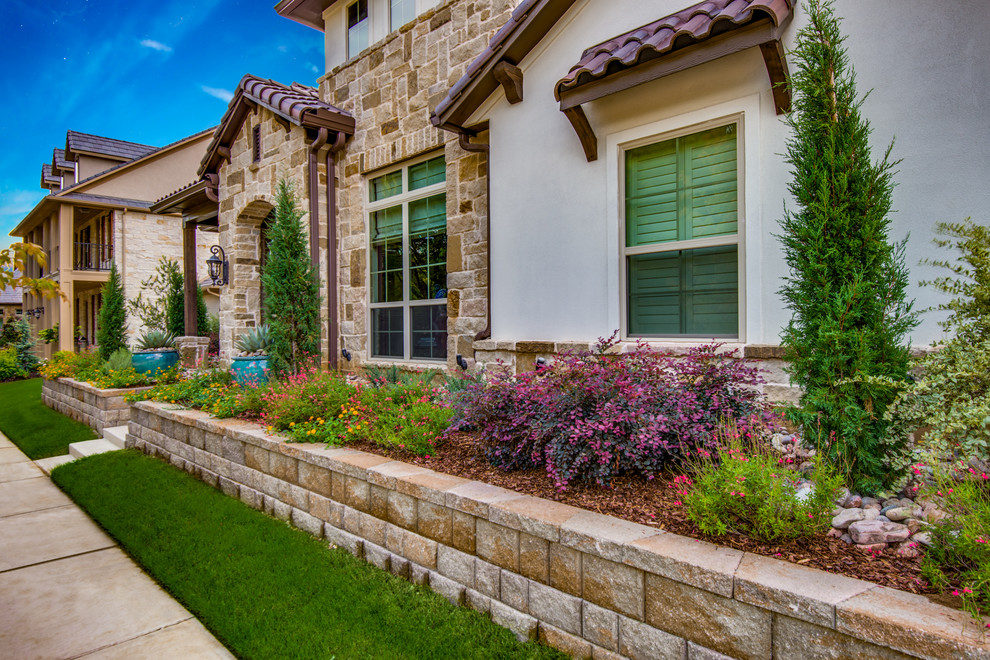 This is an example of a mid-sized mediterranean full sun front yard concrete paver retaining wall landscape in Dallas.