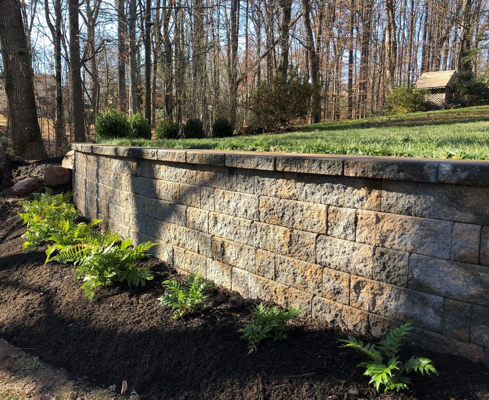Photo of a medium sized classic sloped garden in DC Metro with a retaining wall and concrete paving.
