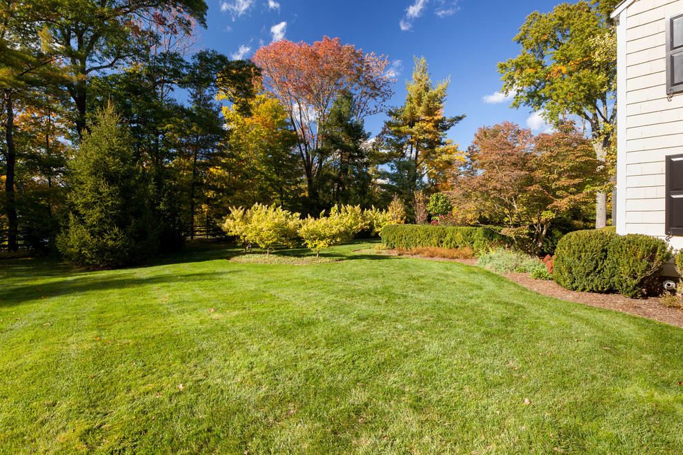Photo of a large traditional front formal partial sun garden for autumn in New York with a garden path and concrete paving.