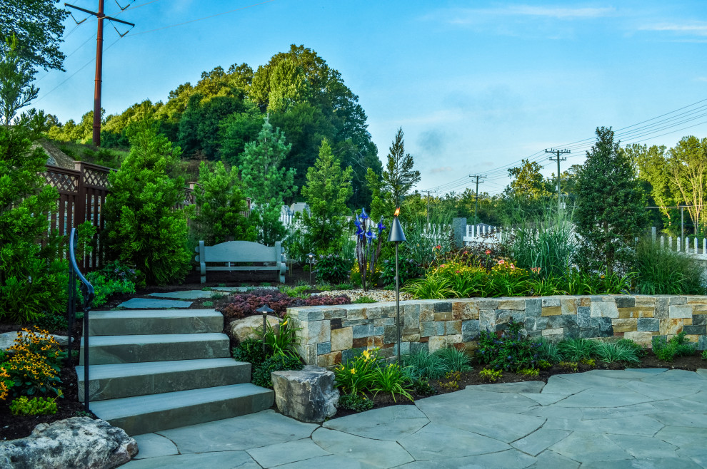Immagine di un grande giardino formale stile americano esposto in pieno sole dietro casa in primavera con un muro di contenimento e pavimentazioni in pietra naturale
