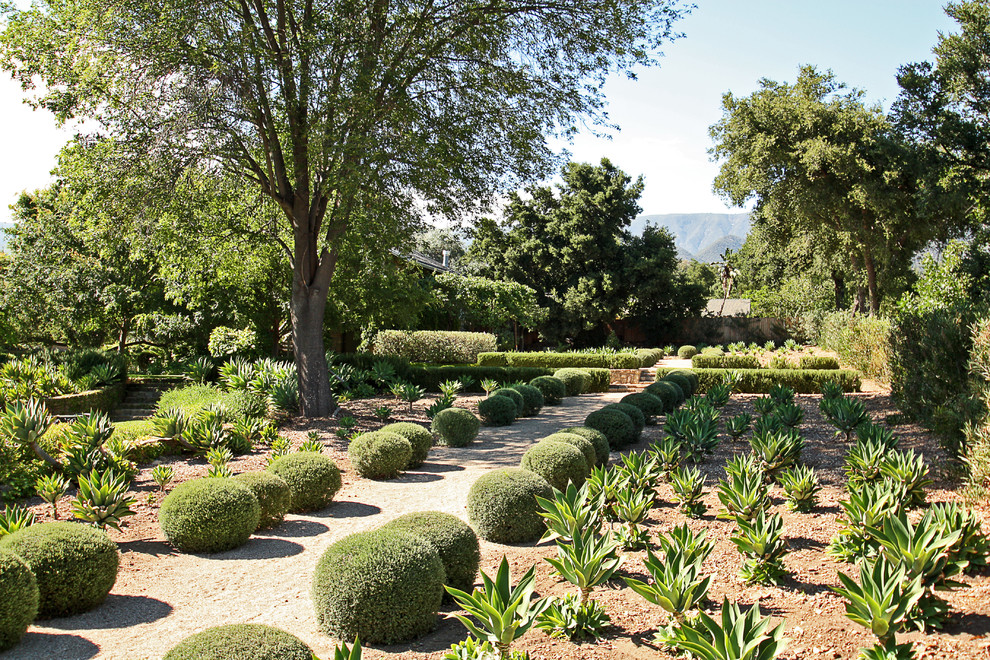 На фото: засухоустойчивый сад на заднем дворе в средиземноморском стиле с покрытием из гравия