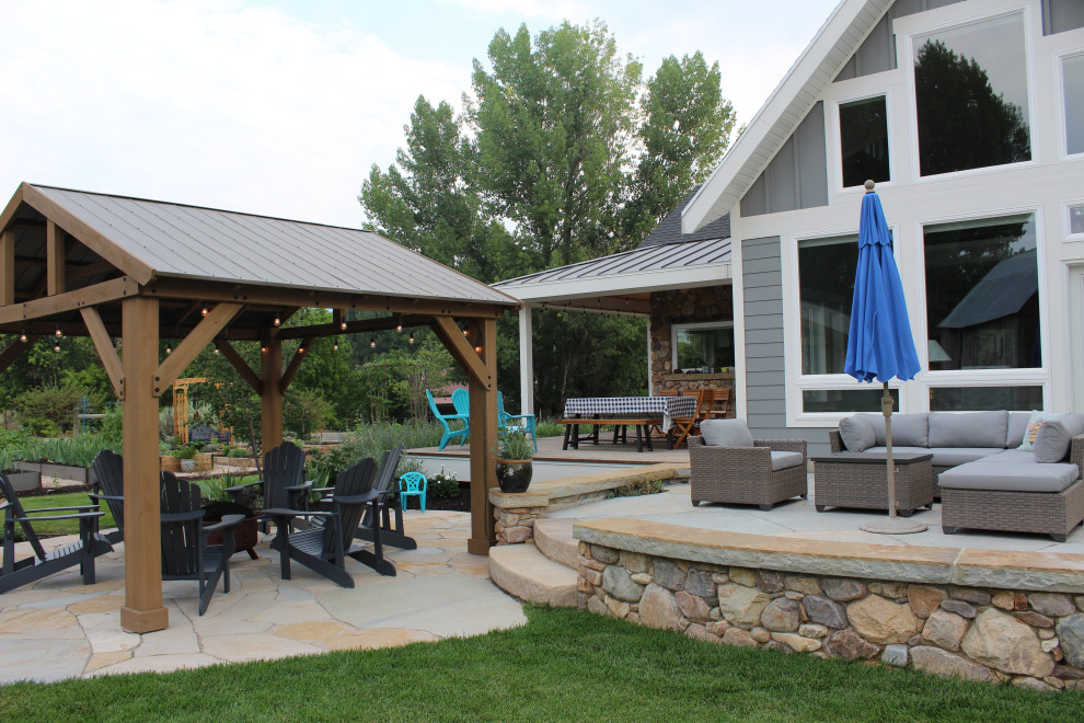 Idée de décoration pour une terrasse arrière champêtre de taille moyenne avec un foyer extérieur et des pavés en pierre naturelle.