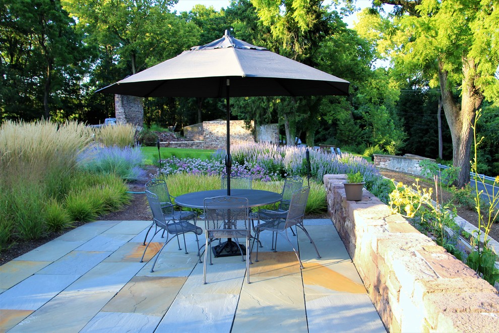 Immagine di un giardino country esposto in pieno sole di medie dimensioni e dietro casa in estate con un muro di contenimento e pavimentazioni in pietra naturale