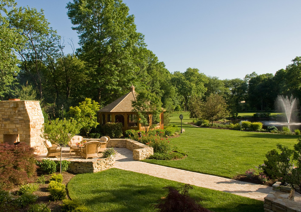 Cette image montre un grand jardin arrière traditionnel avec un point d'eau et des pavés en pierre naturelle.