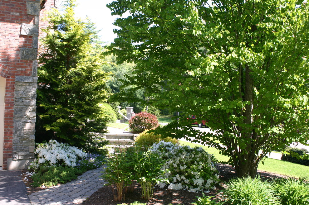 This is an example of a medium sized classic back formal partial sun garden for spring in New York with a retaining wall and mulch.