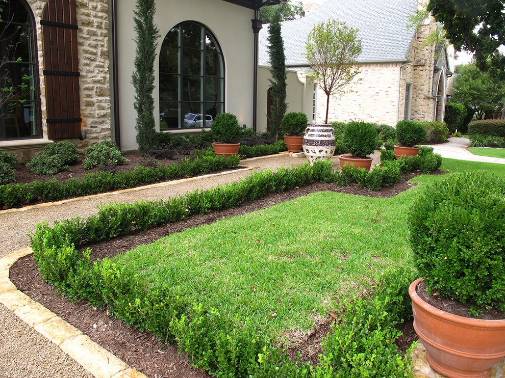 This is an example of a medium sized classic front formal partial sun garden for summer in Dallas with gravel.