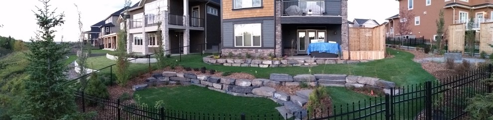 Geräumiger Moderner Garten hinter dem Haus mit Feuerstelle, direkter Sonneneinstrahlung und Mulch in Calgary