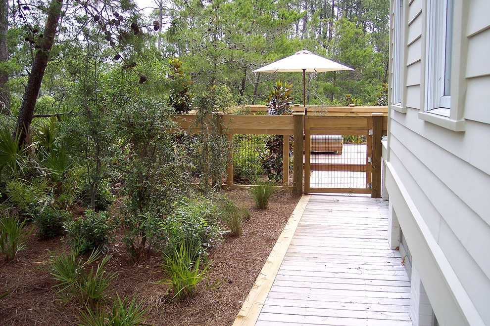 Aménagement d'un jardin latéral bord de mer de taille moyenne et l'été avec une terrasse en bois et une exposition partiellement ombragée.