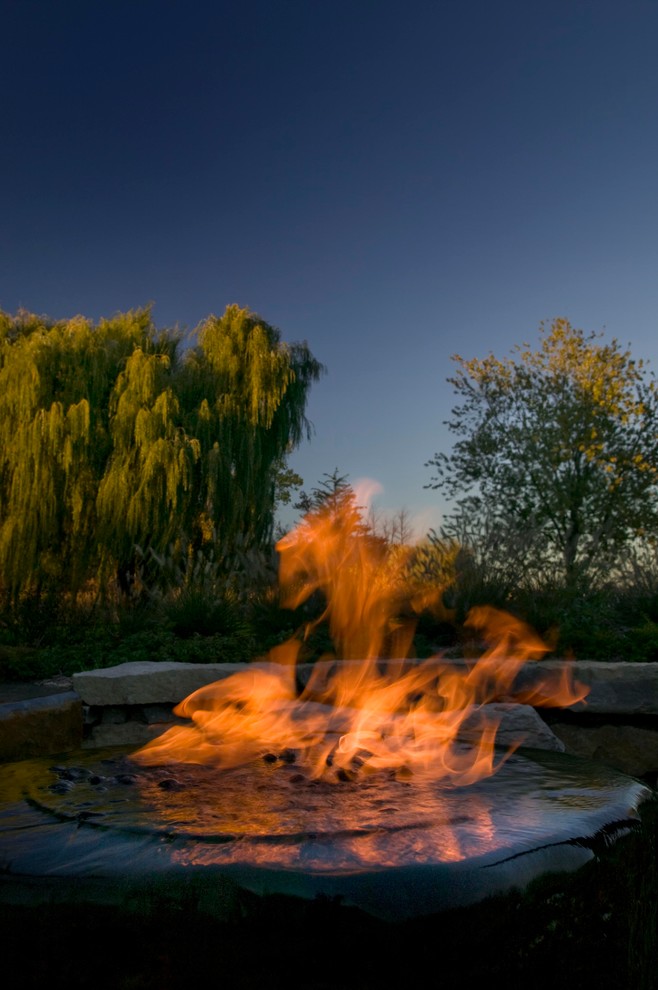 Photo of a mid-sized modern backyard mulch landscaping in Detroit with a fire pit.
