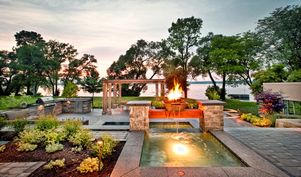 This is an example of a classic back garden in Toronto with a water feature and concrete paving.