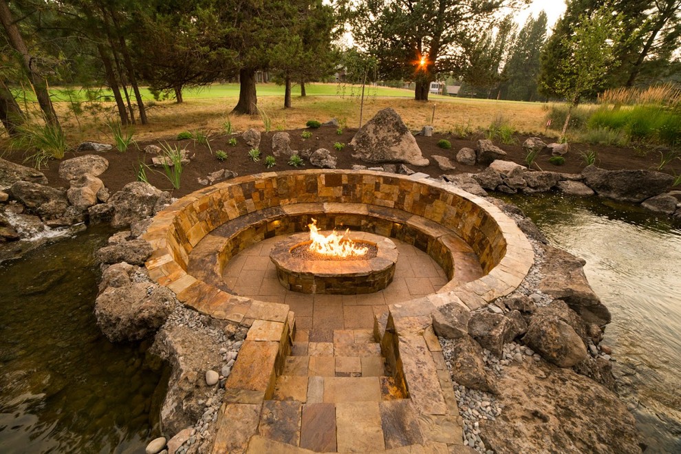 Large traditional back full sun garden in Other with a fire feature and natural stone paving.