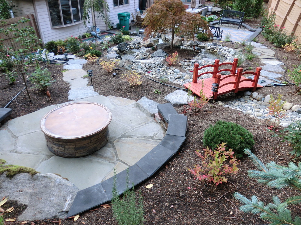 This is an example of a large eclectic backyard concrete paver landscaping in Seattle with a fire pit.