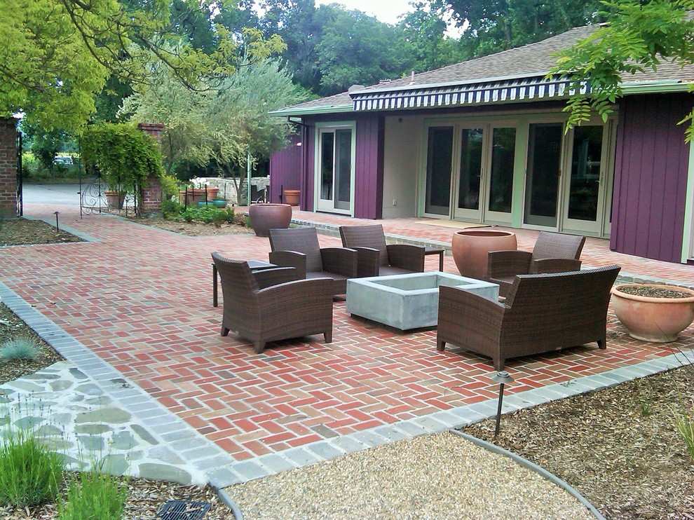 Cette photo montre un jardin arrière moderne de taille moyenne et l'été avec un foyer extérieur, une exposition partiellement ombragée et des pavés en brique.