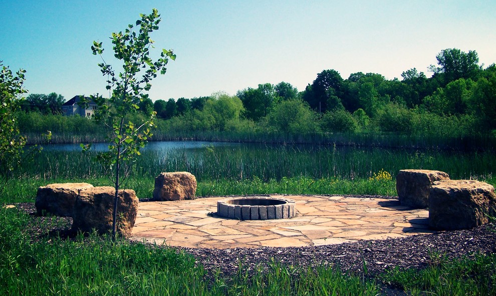 Cette image montre un grand jardin arrière chalet l'été avec une exposition ensoleillée, un foyer extérieur et des pavés en pierre naturelle.