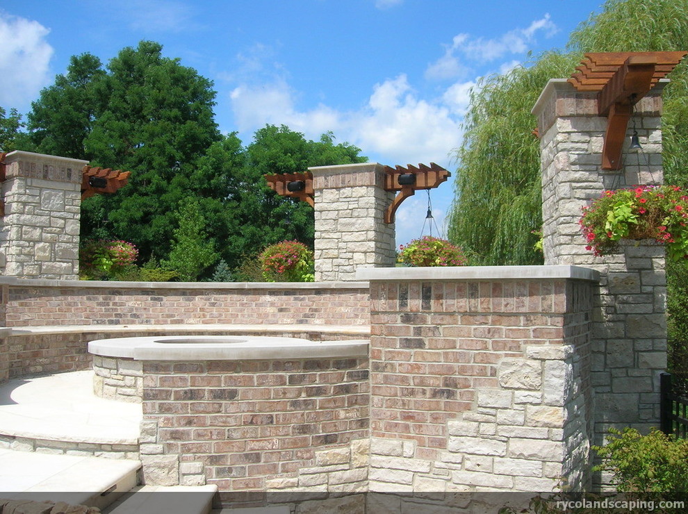 Aménagement d'un jardin arrière classique avec un foyer extérieur, une exposition ensoleillée et des pavés en pierre naturelle.