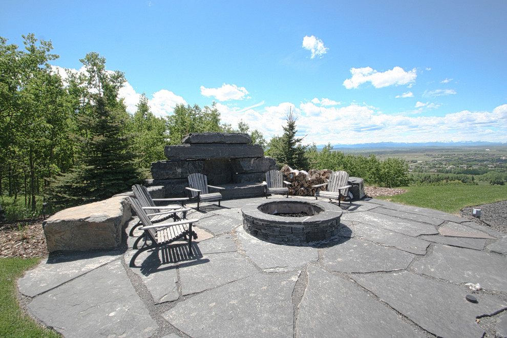 Patio - huge contemporary backyard stone patio idea in Calgary with a fire pit