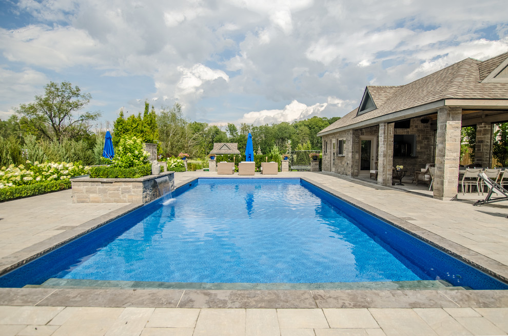 На фото: большой бассейн на заднем дворе в классическом стиле с мощением клинкерной брусчаткой с