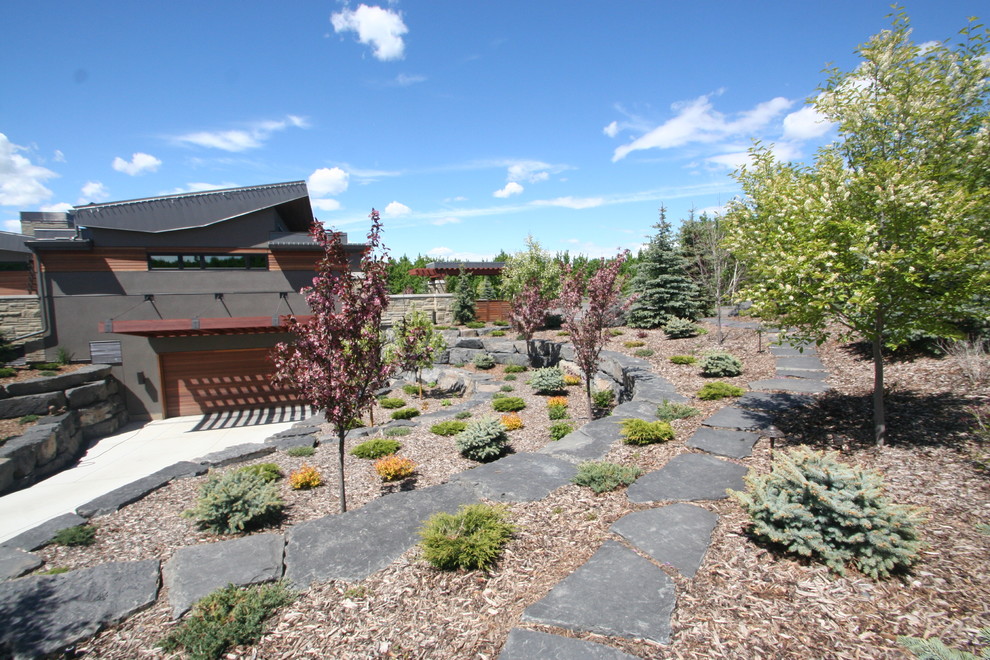 Exemple d'un très grand jardin tendance l'été avec une pente, une colline ou un talus, des pavés en pierre naturelle, un mur de soutènement et une exposition ensoleillée.