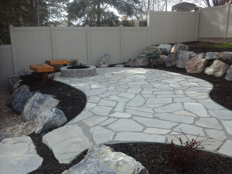 Photo of a large classic back xeriscape partial sun garden for summer in Salt Lake City with a fire feature and natural stone paving.