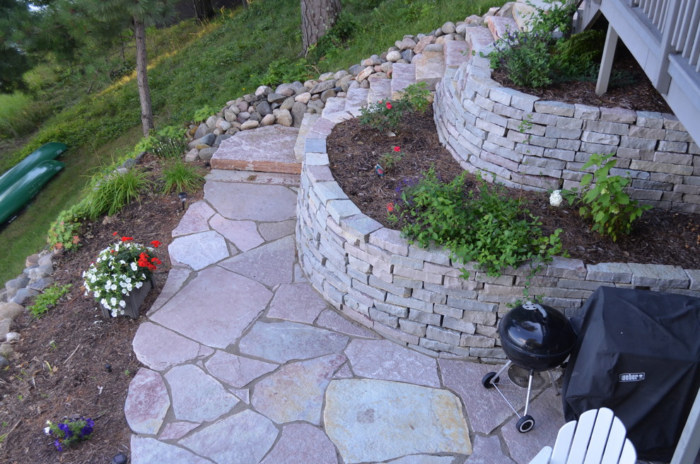Cette image montre un jardin chalet avec des pavés en pierre naturelle, un mur de soutènement et une pente, une colline ou un talus.