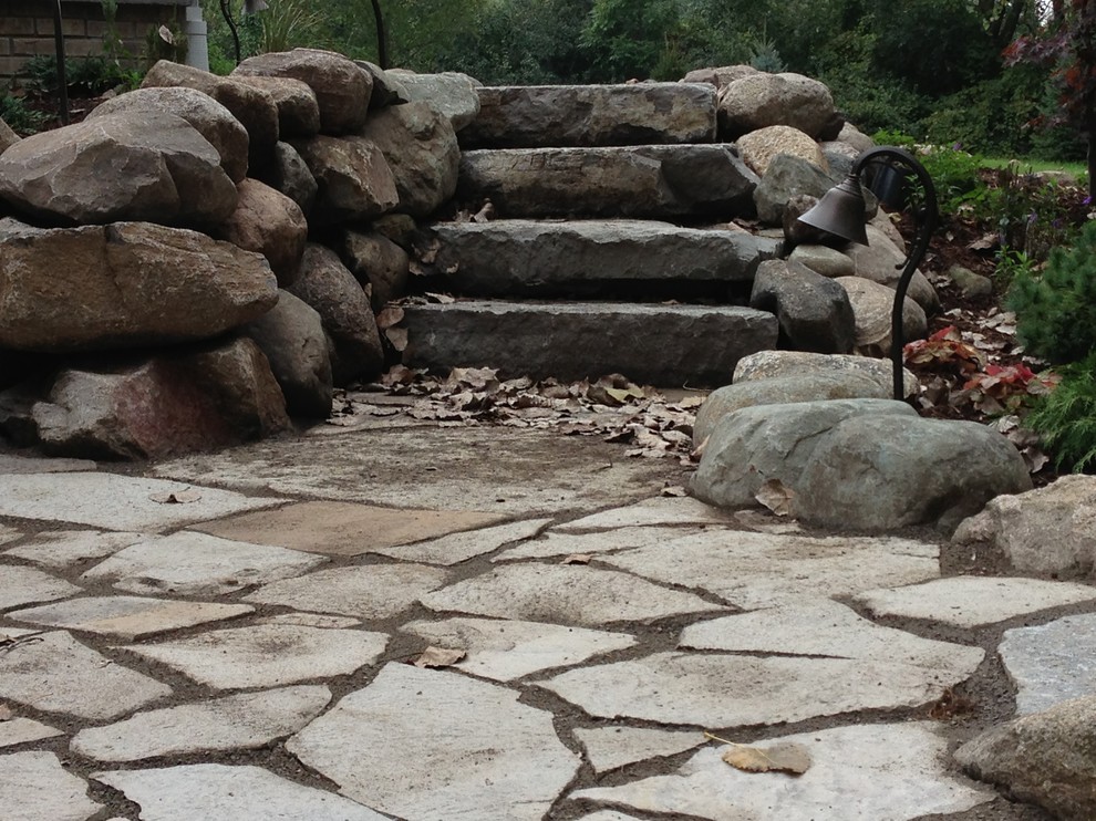 Inspiration for a large rustic full sun backyard stone landscaping in Detroit.