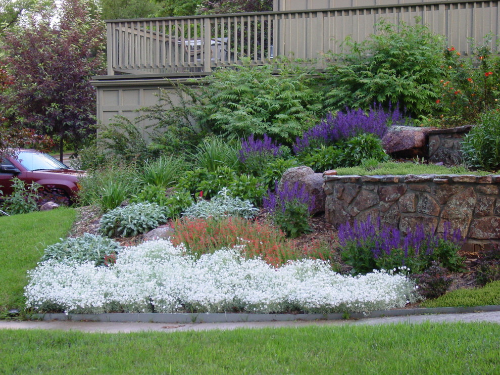 Imagen de jardín clásico grande en patio delantero con muro de contención y adoquines de piedra natural