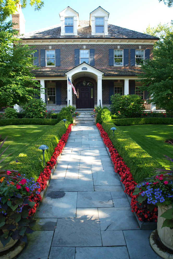 Ispirazione per un giardino formale tradizionale esposto a mezz'ombra di medie dimensioni e davanti casa in estate con pavimentazioni in pietra naturale