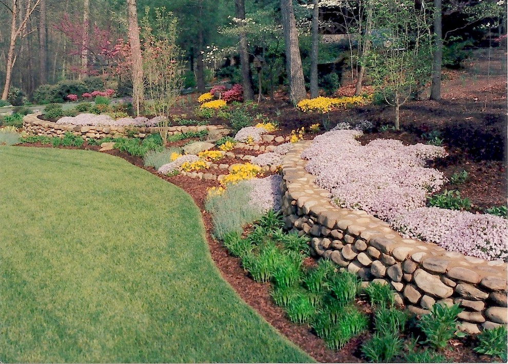 Пример оригинального дизайна: большой весенний, солнечный регулярный сад на переднем дворе в стиле рустика с подпорной стенкой и хорошей освещенностью