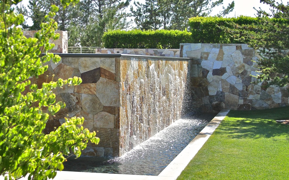 Imagen de jardín moderno grande en verano en patio delantero con fuente, exposición parcial al sol y adoquines de piedra natural