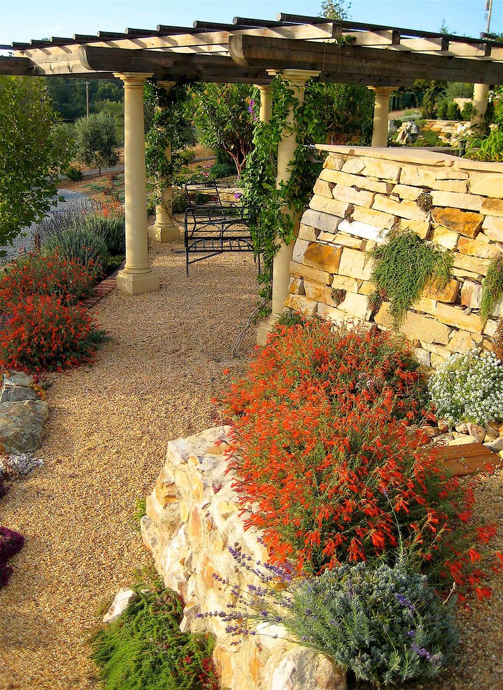 Ejemplo de jardín de secano mediterráneo extra grande en verano en ladera con exposición total al sol y gravilla