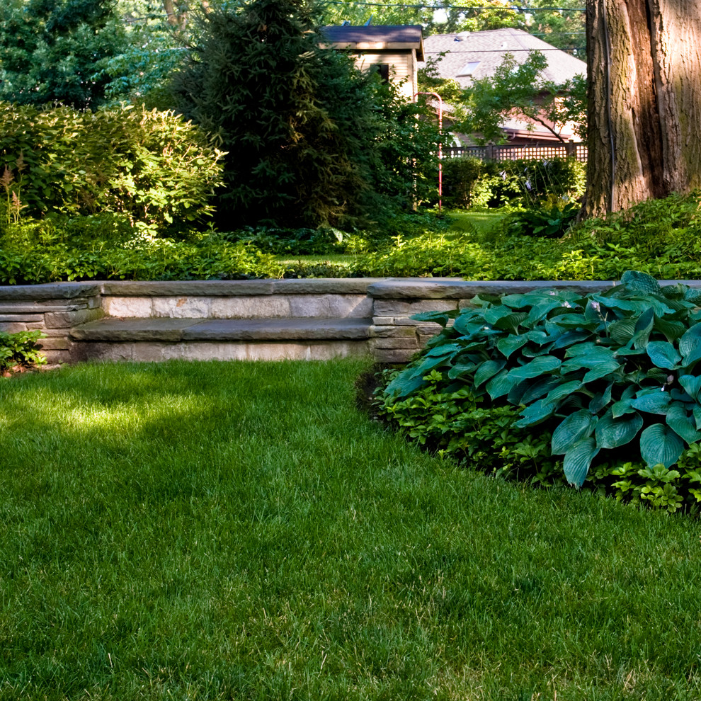 Inspiration för mellanstora klassiska formella trädgårdar i skuggan längs med huset på sommaren, med en trädgårdsgång och naturstensplattor