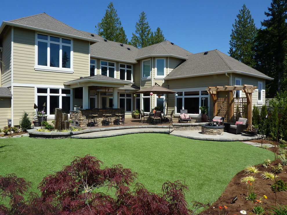 Foto di un grande giardino design esposto in pieno sole dietro casa con pavimentazioni in cemento e un focolare
