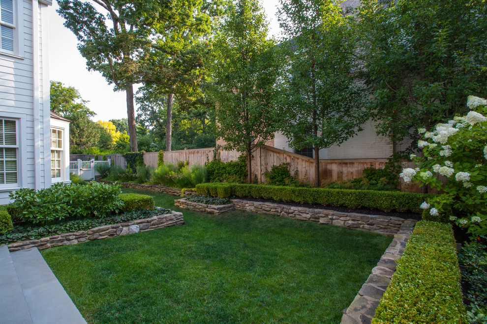 This is an example of a medium sized traditional partial sun garden for summer in Chicago with natural stone paving.