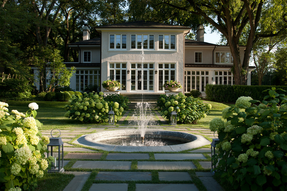 Diseño de jardín clásico grande en patio trasero con fuente y adoquines de hormigón