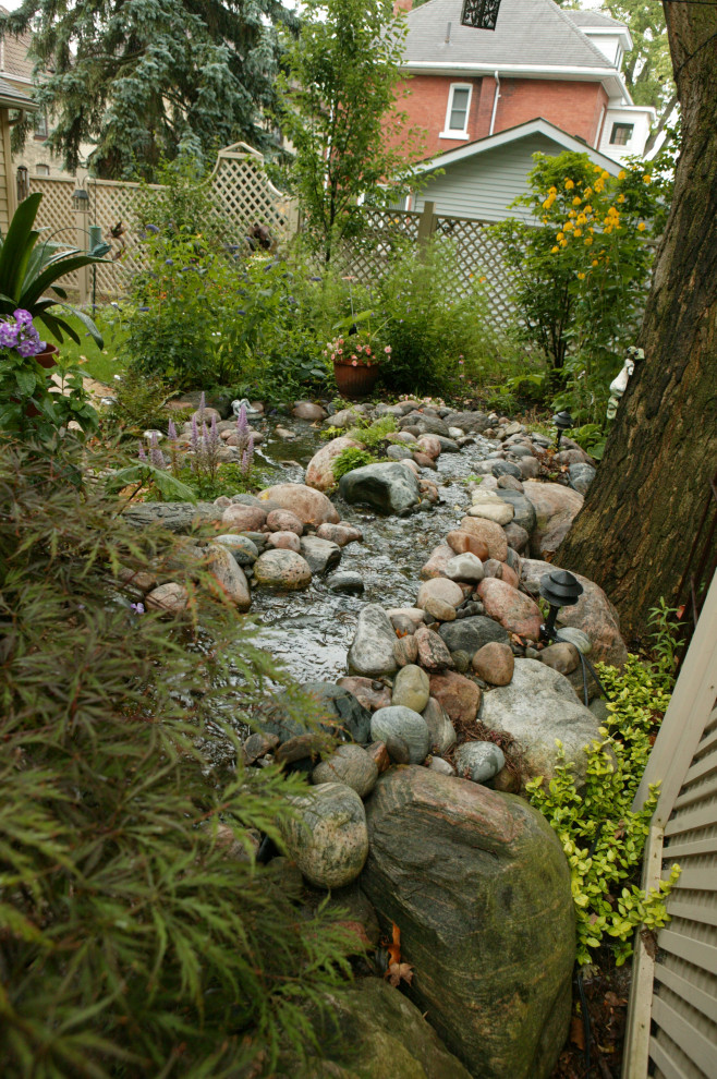 Immagine di un laghetto da giardino chic esposto a mezz'ombra di medie dimensioni e dietro casa in estate con sassi di fiume