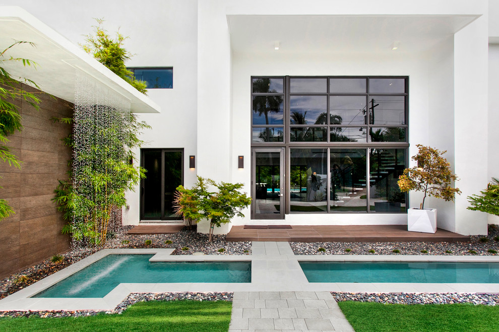 Moderner Garten neben dem Haus mit Wasserspiel und Betonboden in Miami