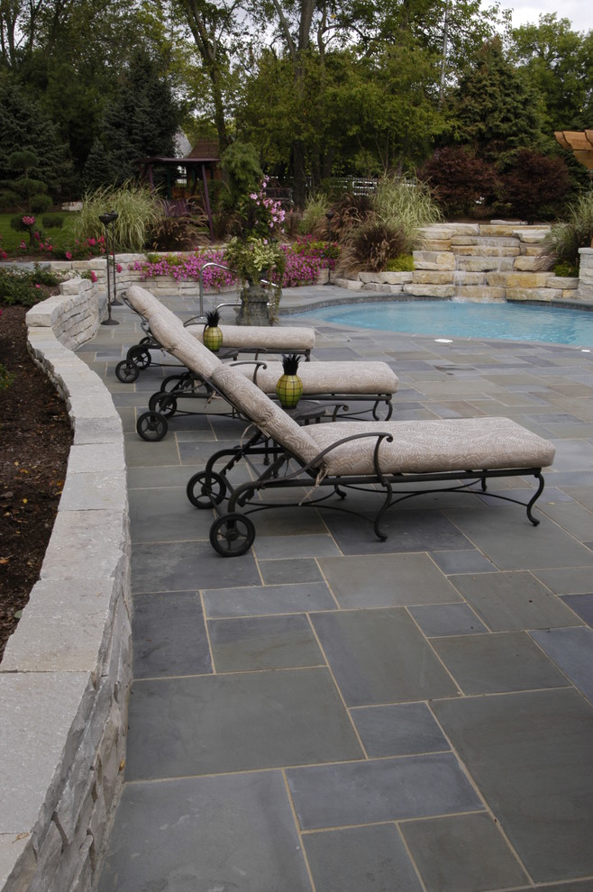 Diseño de jardín clásico extra grande en patio trasero con fuente y adoquines de piedra natural