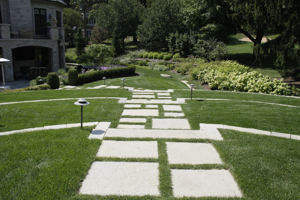 This is an example of a large traditional back garden in Chicago with a retaining wall and natural stone paving.
