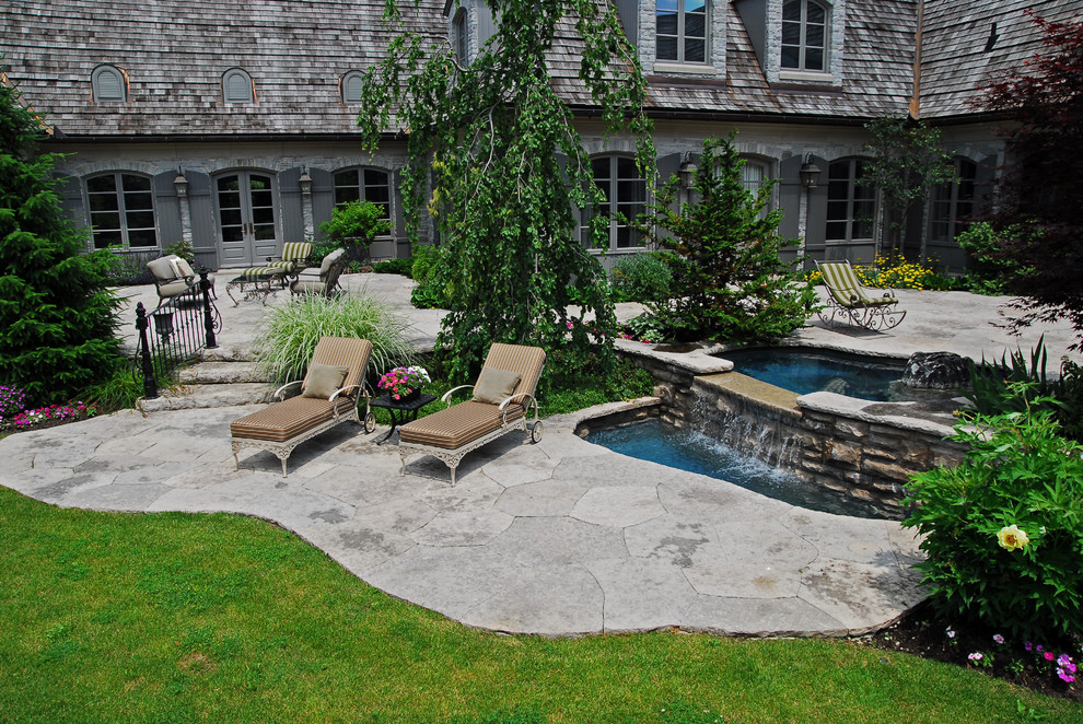Photo of an expansive traditional back partial sun garden for summer in Toronto with a water feature and natural stone paving.