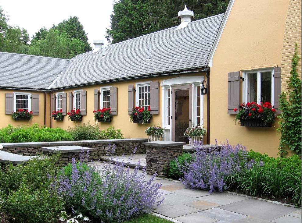 Mittelgroßer, Halbschattiger Garten im Frühling, hinter dem Haus mit Kübelpflanzen und Natursteinplatten in Manchester