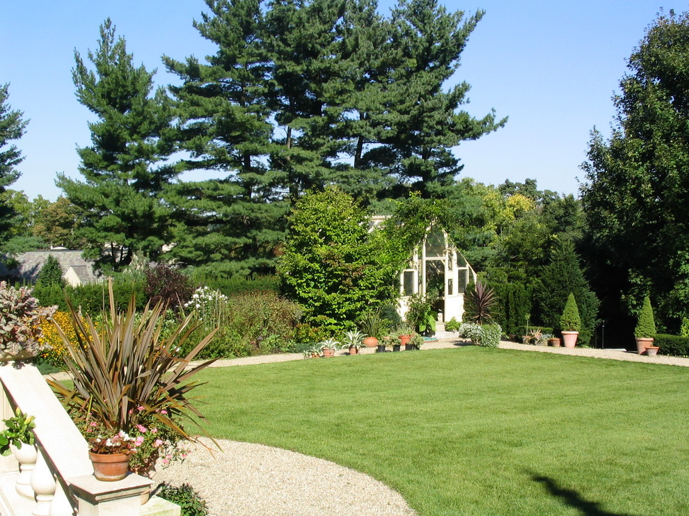 Immagine di un ampio giardino tradizionale esposto a mezz'ombra dietro casa in estate con ghiaia