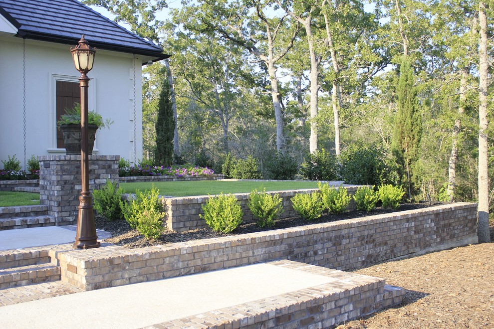 This is an example of a medium sized traditional front driveway partial sun garden for spring in Dallas with a garden path and concrete paving.