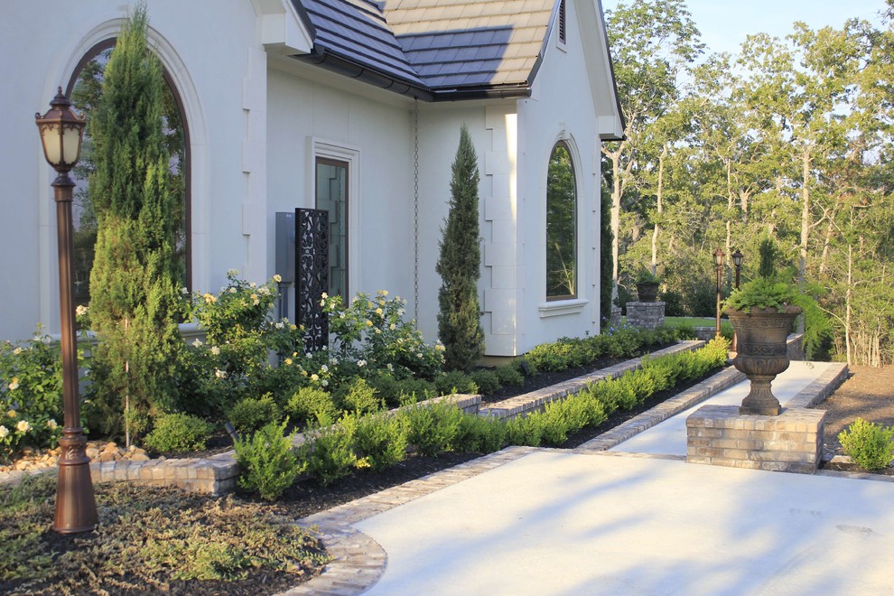 Diseño de jardín clásico de tamaño medio en primavera en patio delantero con adoquines de hormigón y exposición parcial al sol