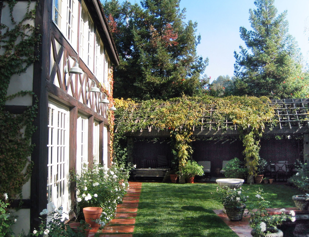 Idées déco pour un grand jardin à la française arrière classique au printemps avec une exposition partiellement ombragée et des pavés en brique.