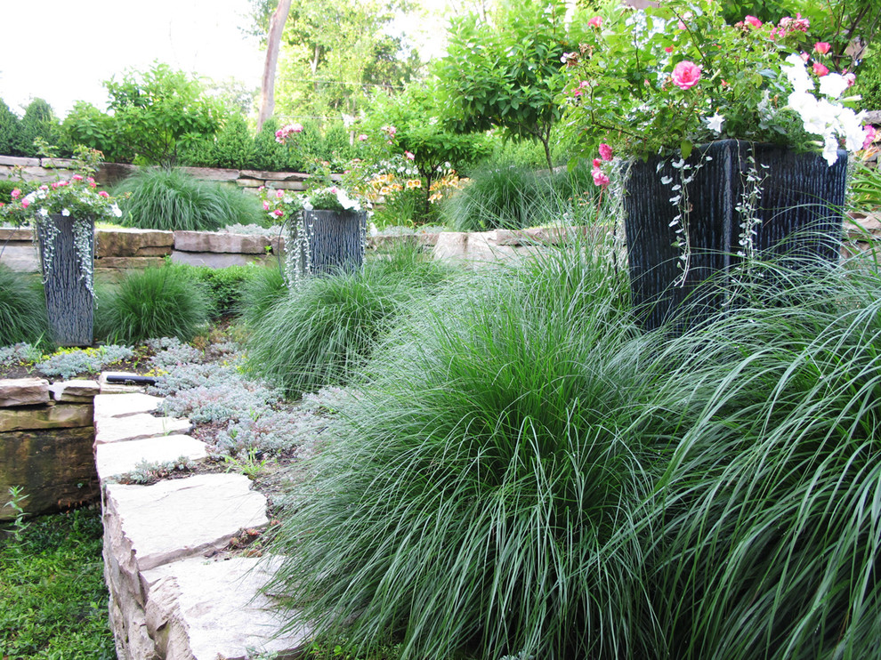 Cette image montre un jardin arrière traditionnel l'été et de taille moyenne avec un mur de soutènement, des pavés en pierre naturelle et une exposition ensoleillée.