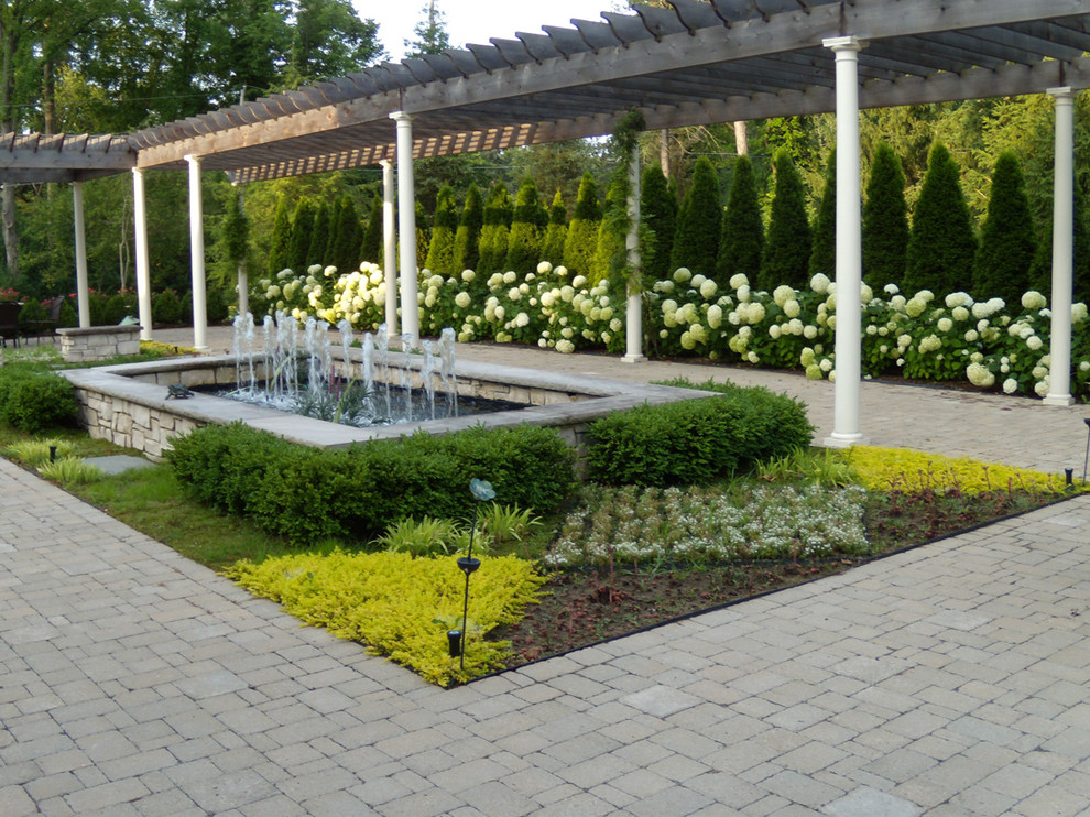 Inredning av en klassisk mycket stor trädgård i delvis sol på sommaren, med marksten i tegel och en fontän