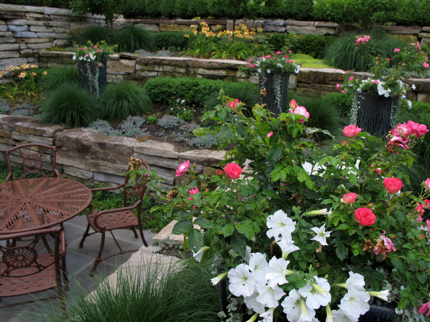 Ejemplo de jardín clásico de tamaño medio en verano en patio trasero con muro de contención, exposición total al sol y adoquines de piedra natural
