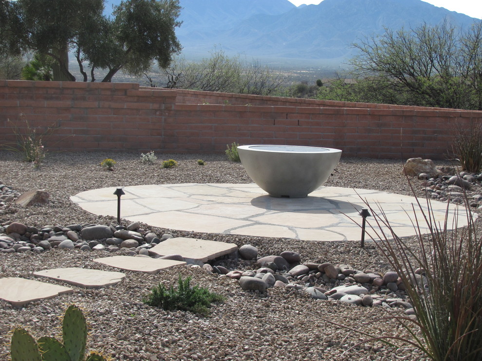 This is an example of a medium sized back xeriscape full sun garden for spring in Other with a fire feature and natural stone paving.